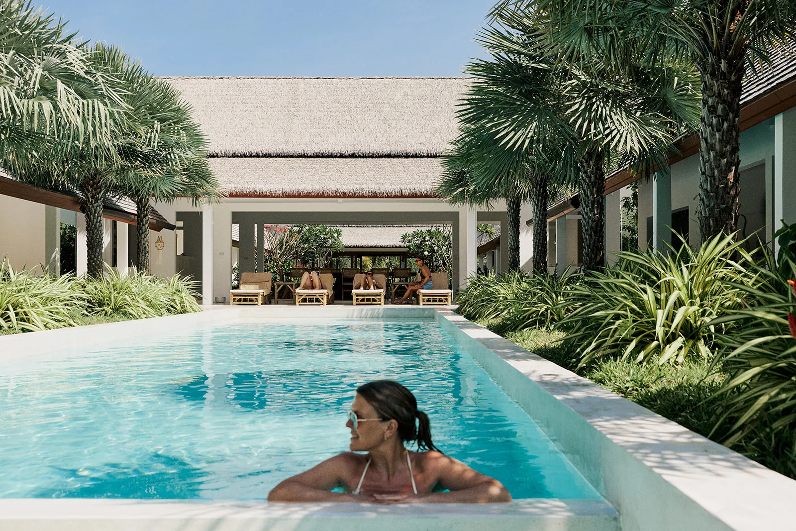 Guest beside Villa Aditi's palm-lined lap pool in the tropical courtyard on Koh Samui