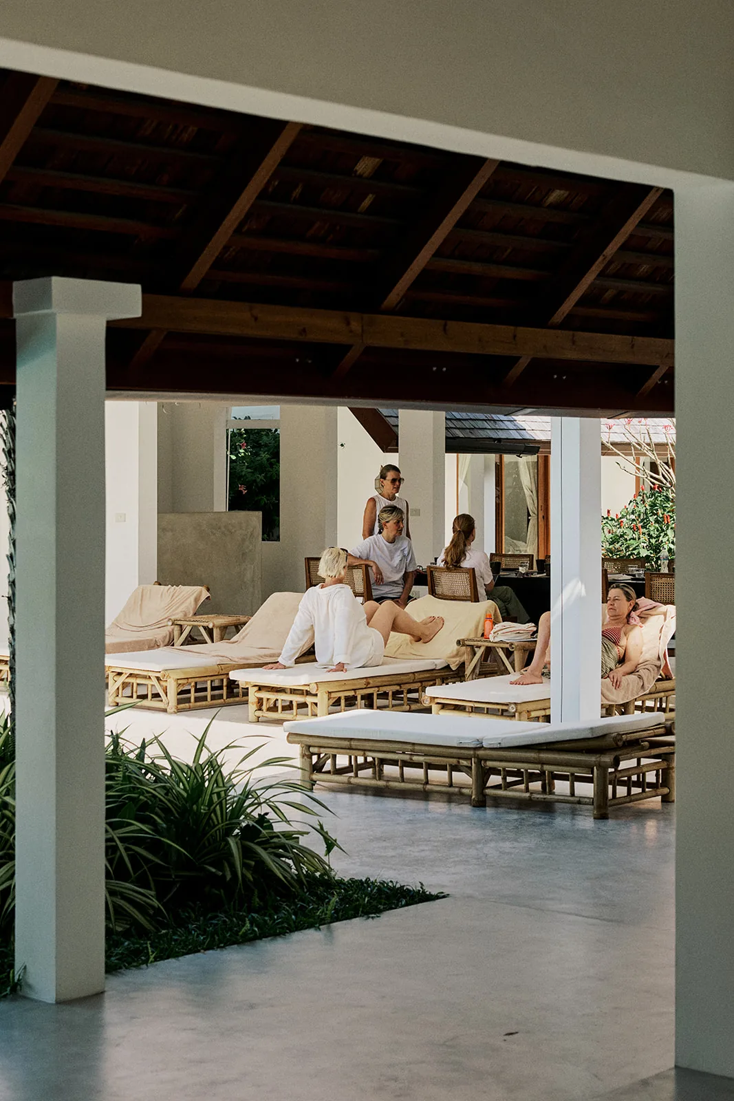 Family unwinding on loungers in the shaded poolside sala