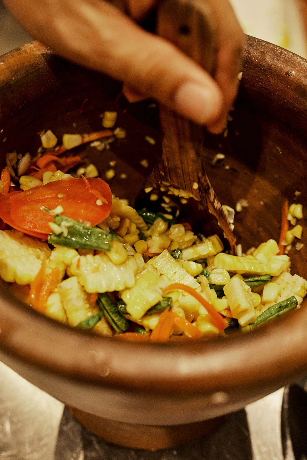 Tossing green papaya salad in a clay mortar
