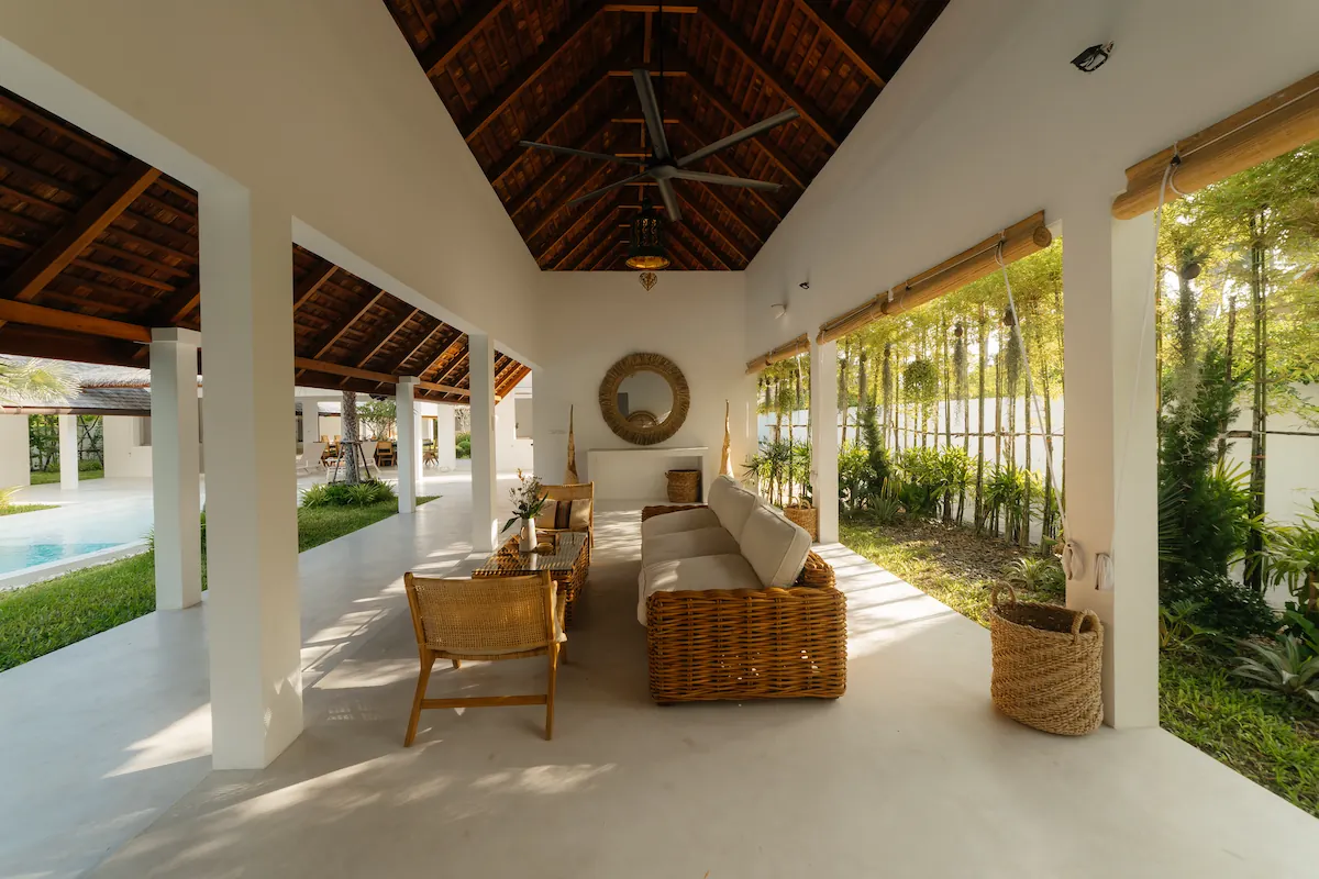 Open-air poolside lounge with rattan furniture under vaulted wooden roof at Villa Aditi, Koh Samui